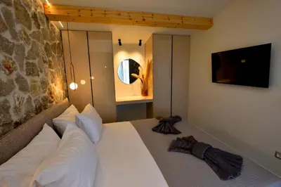 a bedroom with a white bed with a stone wall at Villa 101 Rhodes in Ixia