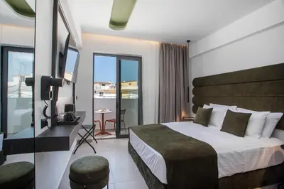 a hotel room with a bed and a desk and a balcony at Ermou 44 City Hotel in Faliraki