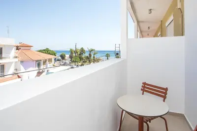 a table and chair on a balcony with a view of the ocean at Ermou 44 City Hotel in Faliraki