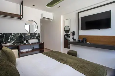 a hotel room with a bed and a flat screen tv at Ermou 44 City Hotel in Faliraki
