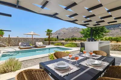 a patio with a table and chairs and a swimming pool at Villa Zen Zazan by Villa Plus in Kolimbia