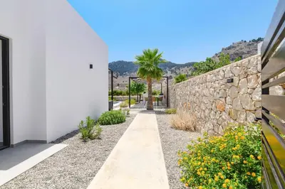 a garden with a stone wall and a palm tree at Villa Zen Zazan by Villa Plus in Kolimbia