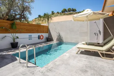 a swimming pool with a chair and an umbrella at Aura Luxury Villas in Kolimbia