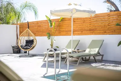 a patio with a table and chairs and an umbrella at Aura Luxury Villas in Kolimbia