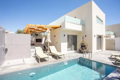 a villa with a swimming pool and a house at Aura Luxury Villas in Kolimbia