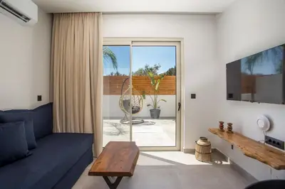 a living room with a blue couch and a sliding glass door at Aura Luxury Villas in Kolimbia