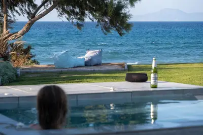 a woman sitting in a swimming pool looking at the ocean at Villa Ramann, Rhodes in Rhodes Town