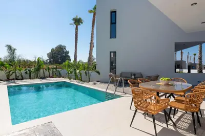 a patio with a table and chairs next to a swimming pool at Davlakos Apartments Rea in Kremasti