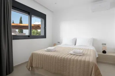 a white bedroom with a bed with two towels on it at Davlakos Apartments Rea in Kremasti