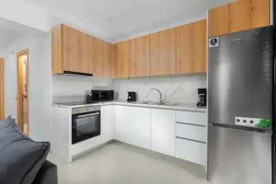 a kitchen with white cabinets and a stainless steel refrigerator at Davlakos Apartments Rea in Kremasti