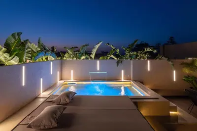a swimming pool with two loungers on a patio at Hamilton Elite Penthouse in Rhodes Town