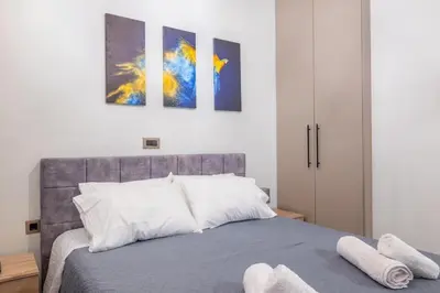a bedroom with a bed and three paintings on the wall at Corner Apartment in Ialyssos