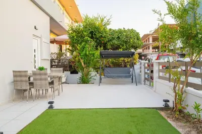 a patio with a table and a grill and grass at Corner Apartment in Ialyssos