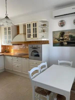 a kitchen with white cabinets and a table and a table and a dining room at Xenia Terra in Kiotari