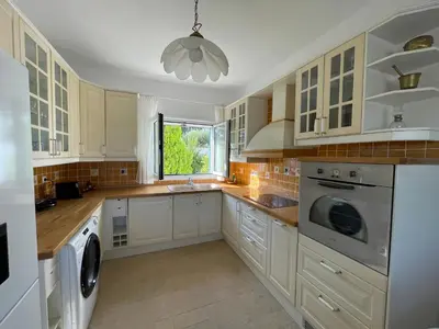 a large kitchen with white cabinets and a window at Xenia Terra in Kiotari