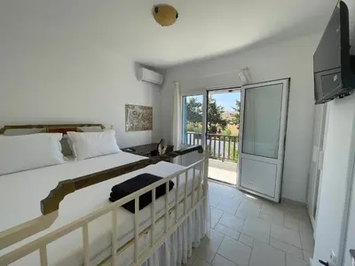 a bedroom with a bed and a balcony at Xenia Terra in Kiotari