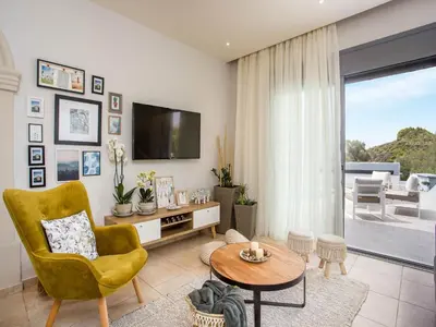 a living room with a yellow chair and a television at 2-Bedroom Villa with Private Pool in Kalithies in Faliraki