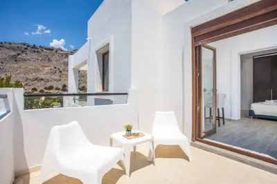 a white house with a balcony with white chairs and a table at Aggelina Pefkos in Pefki Rhodes