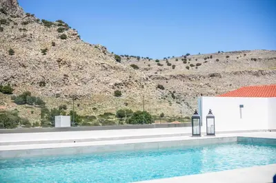 a swimming pool in front of a building with a mountain at Aggelina Pefkos in Pefki Rhodes