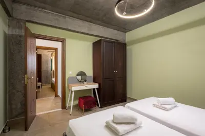 a bedroom with two beds and a desk and a table at Alki Slow Living Apartments in Rhodes Town