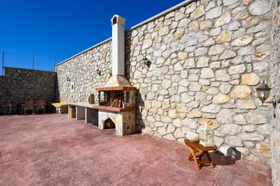 a stone wall with an outdoor fireplace on a patio at Alki Slow Living Apartments in Rhodes Town