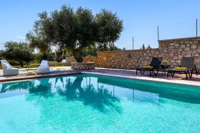 a swimming pool with two chairs and a tree at Alki Slow Living Apartments in Rhodes Town