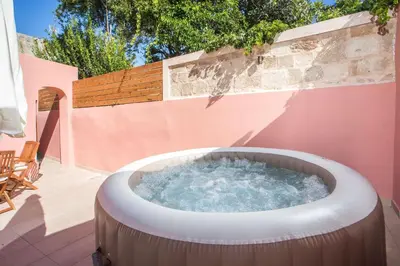 a hot tub on a patio with a fence at Elysian Suite in Rhodes Town