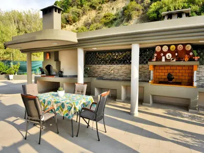 a patio with a table and chairs and a fireplace at Elegant Villa with Pool & Garden in Eleousis in Kalithies