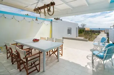 a patio with a white table and chairs at The Cottage South Escape with beach front pool in Plimmiri