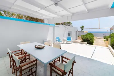 a dining room with a table and chairs on a patio at The Cottage South Escape with beach front pool in Plimmiri