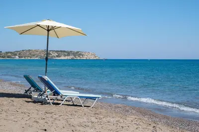 two chairs and an umbrella on a beach at The Cottage South Escape with beach front pool in Plimmiri