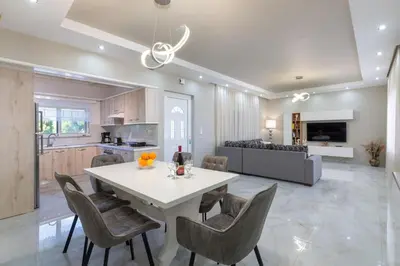 a kitchen and living room with a white table and chairs at The Cottage South Escape with beach front pool in Plimmiri
