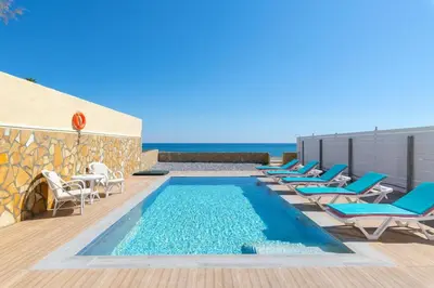 a pool with chairs and the ocean in the background at The Cottage South Escape with beach front pool in Plimmiri