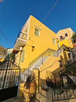 a yellow building with a staircase in front of it at Villa Salachouri in Symi