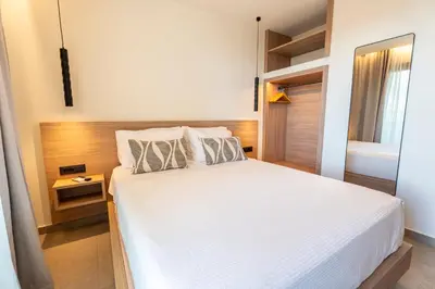 a bedroom with a white bed with a wooden headboard at Naiades Guest House in Sálakos