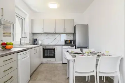 a kitchen with white cabinets and a table and chairs at Villa Amethyst Gem by Villa Plus in Gennadi