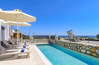 a pool with chairs and an umbrella on a building at Villa Amethyst Gem by Villa Plus in Gennadi