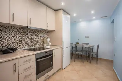 a kitchen with white cabinets and a table with chairs at La Casa Di Kika in Malona Village