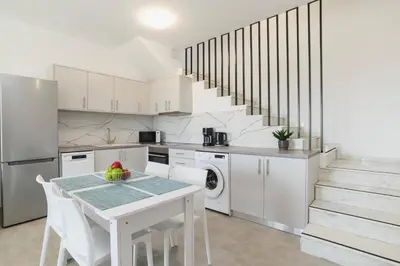 a white kitchen with a table and a staircase at Villa Ruby Gem by Villa Plus in Gennadi