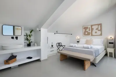 a white bedroom with a bed and a tv at Lindian Poem Villas in Líndos
