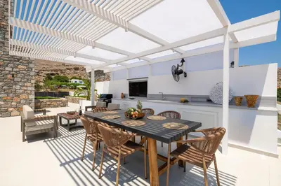 a patio with a table and chairs under a white pergola at Lindian Poem Villas in Líndos