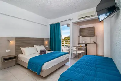 a bedroom with a bed and a kitchen with a table at Anika Studios Faliraki in Faliraki