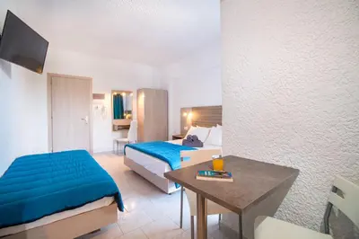 a hotel room with a bed and a desk and a bed and a table at Anika Studios Faliraki in Faliraki