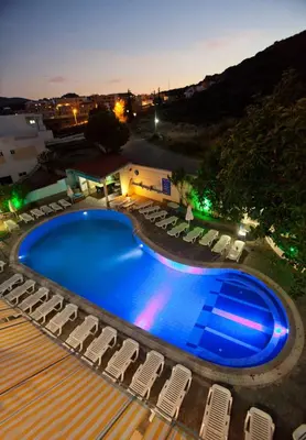 a swimming pool with lounge chairs around it at night at Anika Studios Faliraki in Faliraki