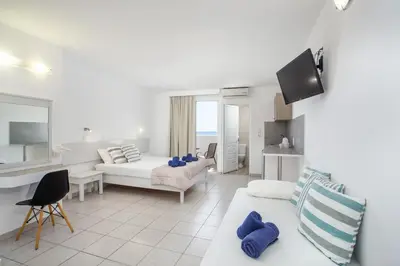 a white living room with a couch and a table at Anika Studios Faliraki in Faliraki