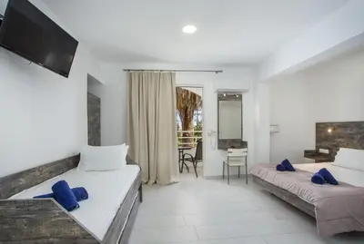 a hotel room with two beds and a desk at Anika Studios Faliraki in Faliraki