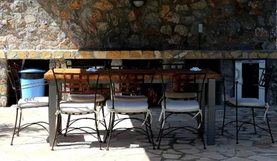 a bar with four chairs and a table with a stone wall at Villa Cleoboulos in Líndos