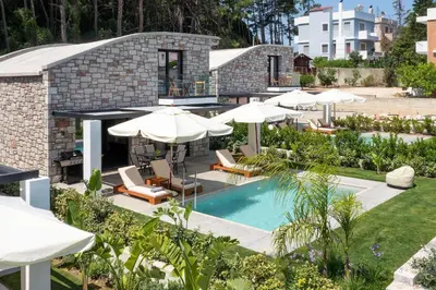 an outdoor swimming pool with umbrellas and chairs at Rokas Luxury Villas in Asgourou