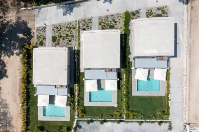 an overhead view of three houses and a pool at Rokas Luxury Villas in Asgourou