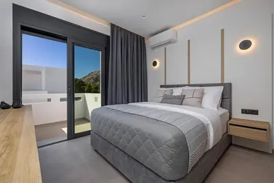 a bedroom with a large bed and a balcony at Amani Villas Lindos in Líndos